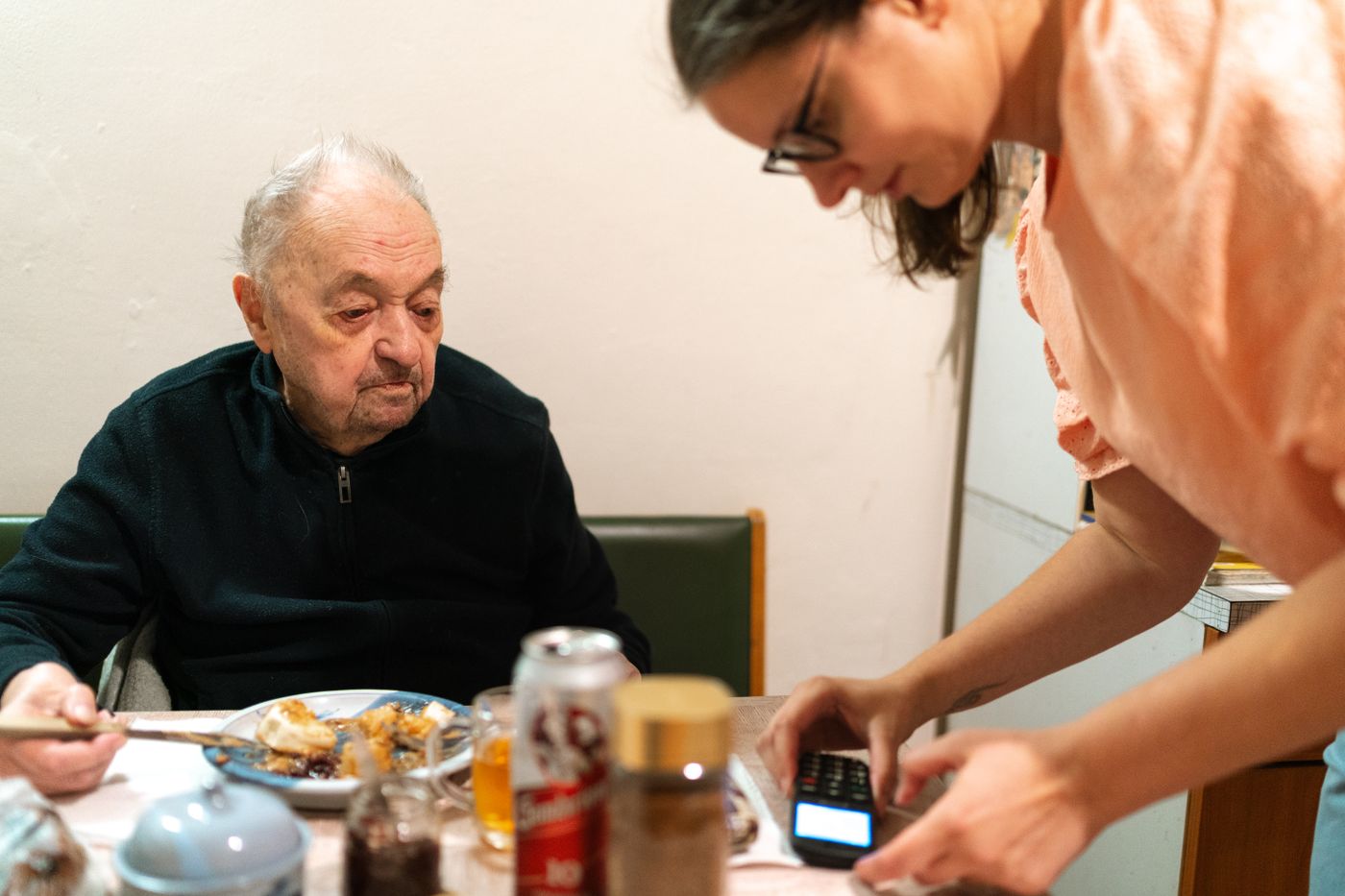 Caregiver helping an older adult at home with a simple TV remote