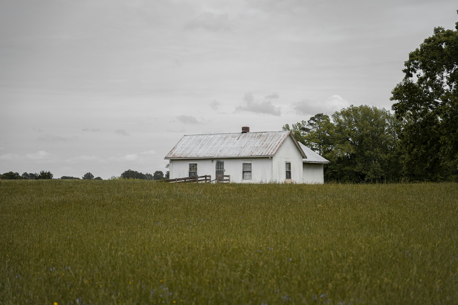 A white farmhouse in a wide green field.